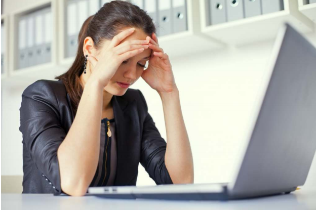 woman holding head in front of laptop
