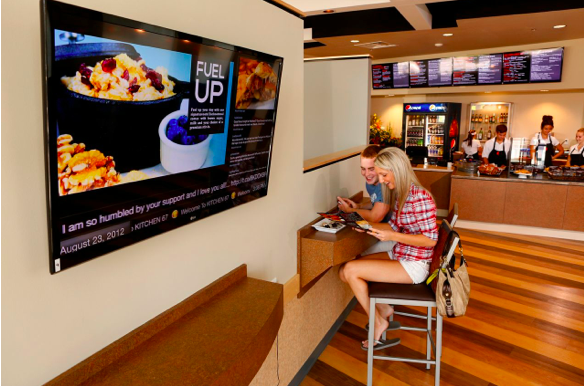  a billboard in front of the couple inside a restaurant