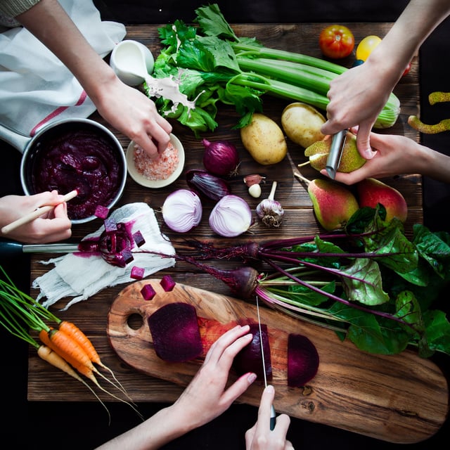 three people chopping veggies on the table