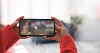 Woman holding smartphone while watching a video