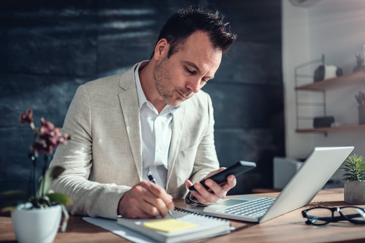  A man working using his phone and laptop