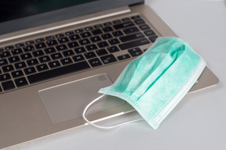 A laptop and a medical mask on top of it.