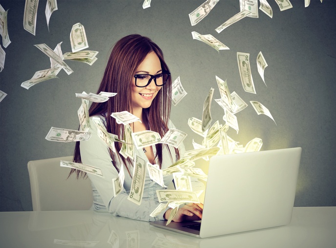 Woman working on a laptop with cash all around