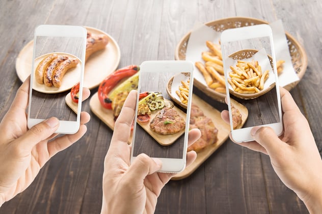 Three people taking pictures of food on the table