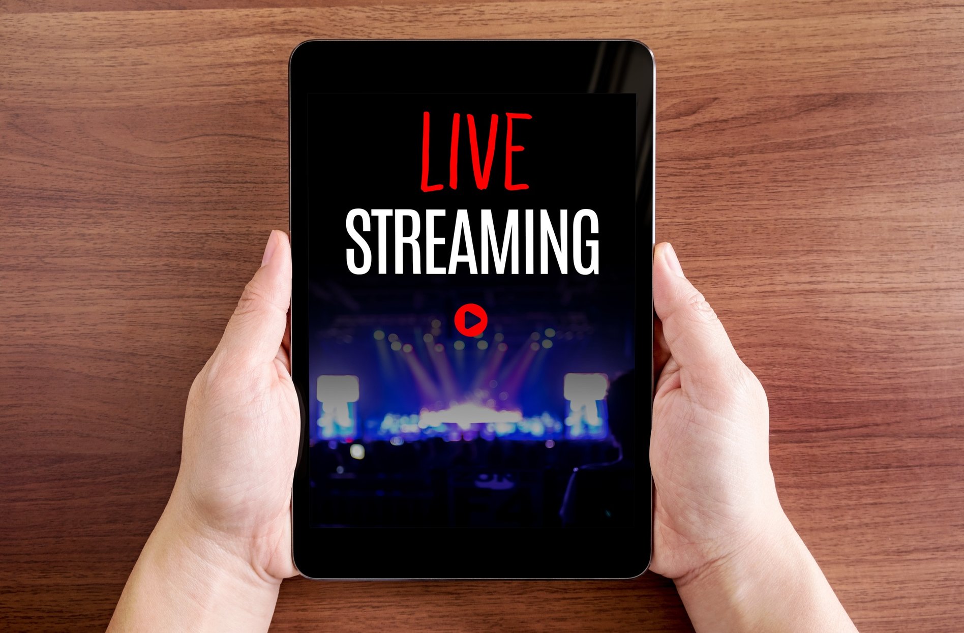  A person holding a tablet with a Facebook Live streaming video of a concert on the screen.