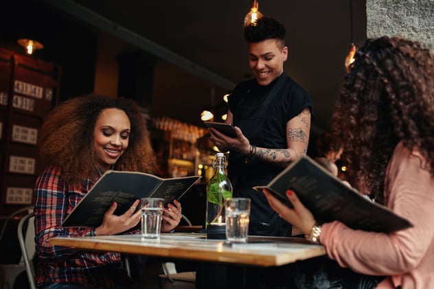 two ladies ordering food to a waiter