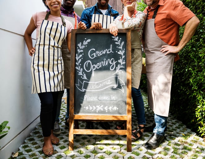 People smiling posing for a picture for their grand opening