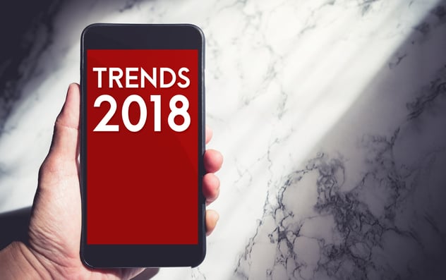 a hand with a phone showing trends 2018