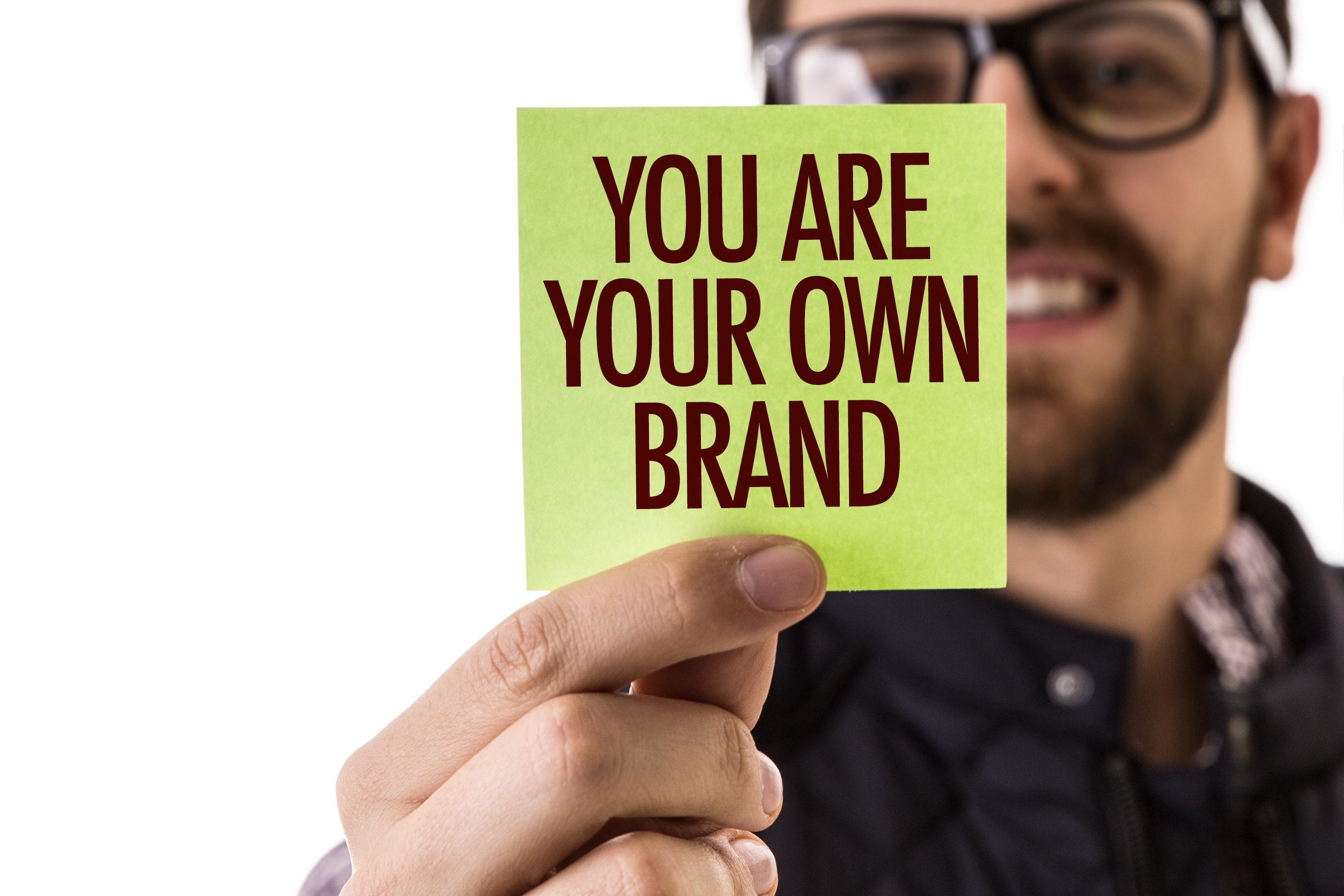 A man with glasses holding a note You are your own brand.