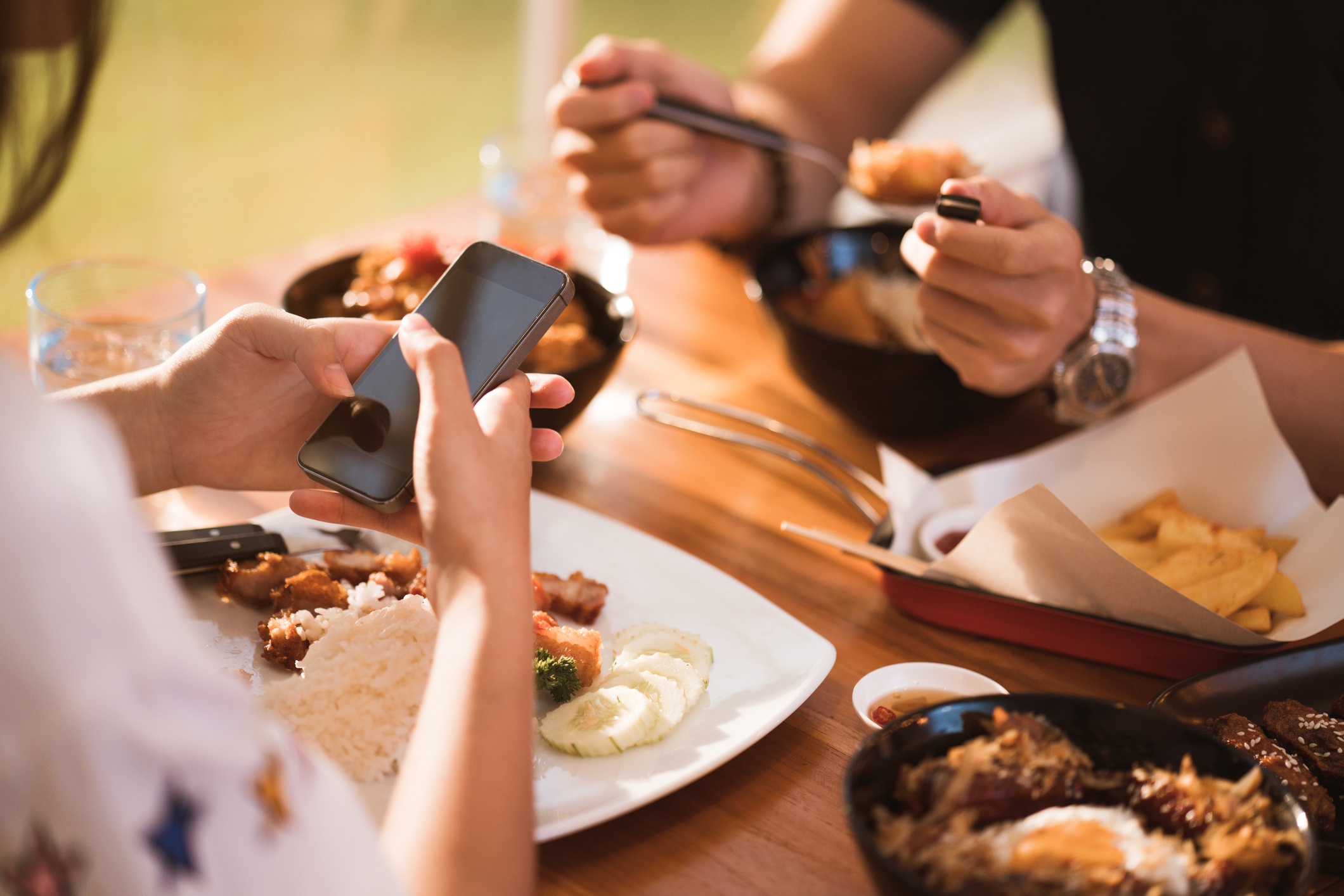 A woman browsing her phone while having a meal with his partner