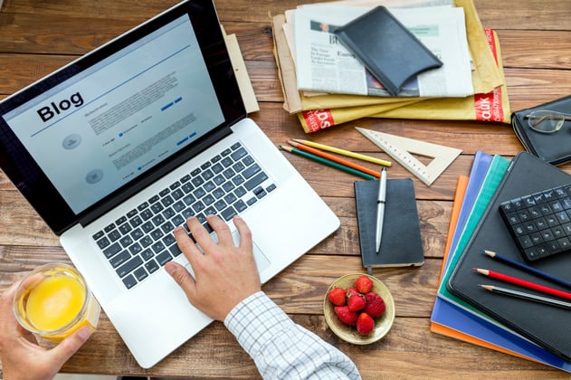 A mans hand working on his laptop with a glass of juice on the other hand