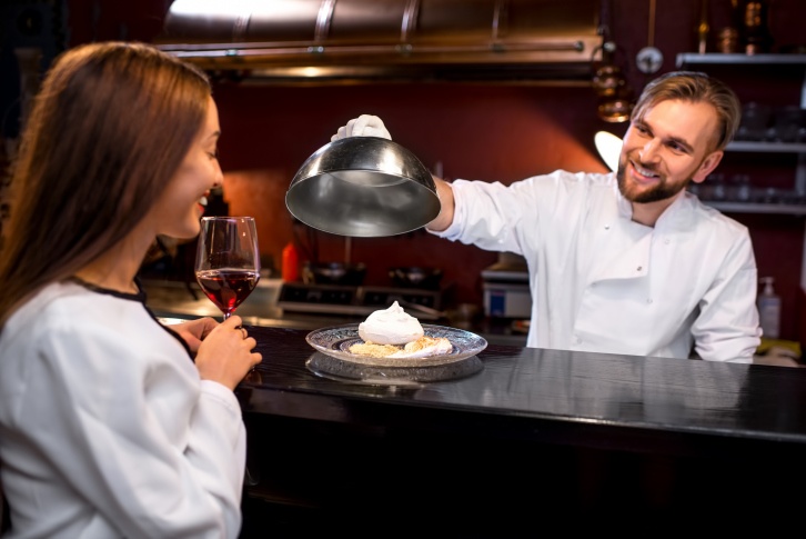 a chef serving the menu to the woman